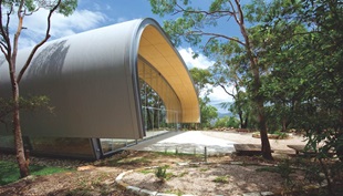 The structural steel bracing is integrated with the upturned hull-like roof, which is clad with LYSAGHT CUSTOM ORB® profile made from COLORBOND® Ultra Steel in the colour Dune®.
